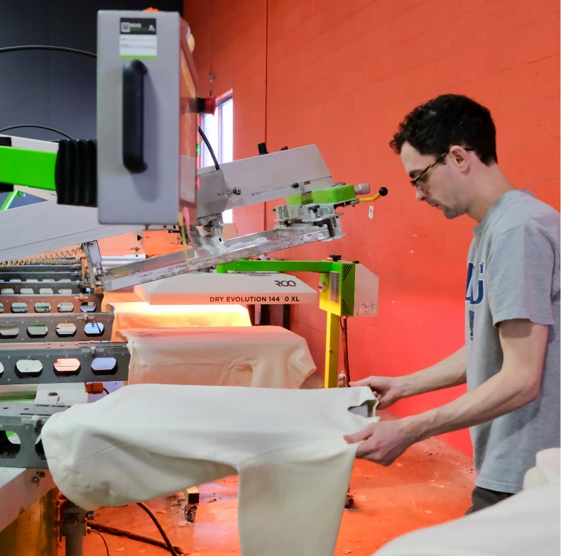 Operator loading garment onto press under orange studio lighting
