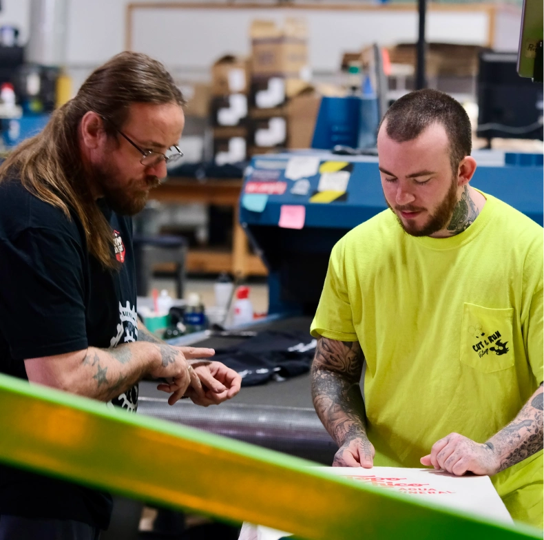 Two team members reviewing artwork at screen printing press