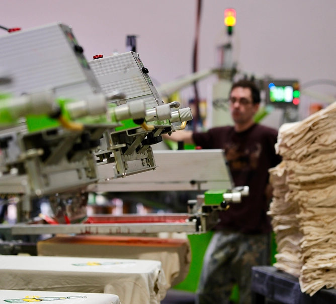 Screen printing press in motion inside production shop