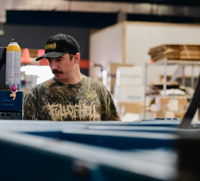 Team member operating screen printing press in production area